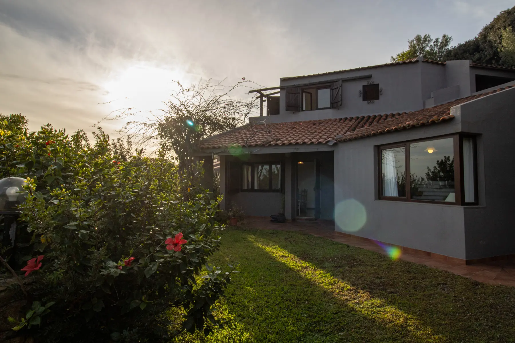 Villa con tetto in coppi, giardino e ibisco al tramonto